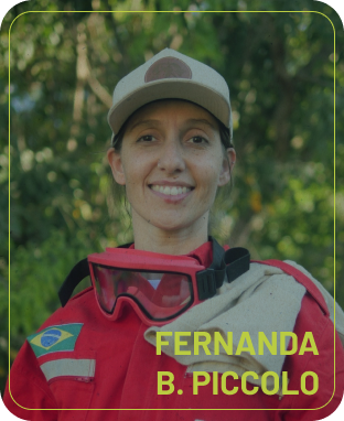 Retrato de Fernanda B. Piccolo, brigadista da BRIVAC, mulher sorrindo de boné, macacão vermelho de combate e óculos de proteção no pescoço. No canto inferior do card, o texto em amarelo lê 'FERNANDA B. PICCOLO'.